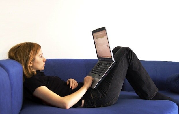 Woman lay on a sofa with a laptop